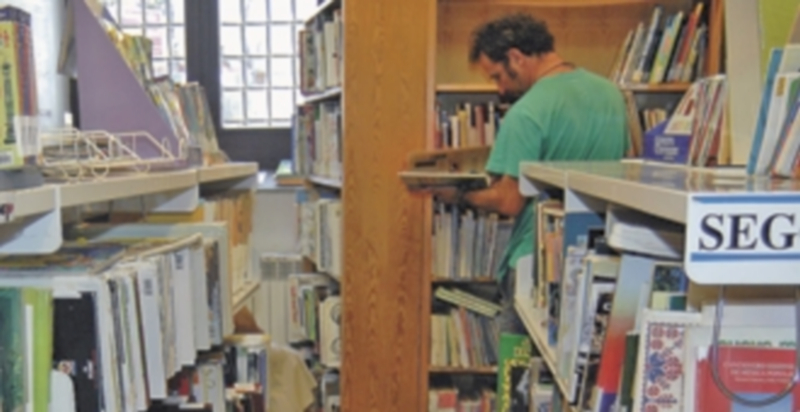 Dos empleados de la Biblioteca revisan los fondos de libros de la sección infantil y juvenil. / Elena Peña