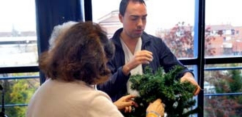 Un monitor de la asociación ayuda a una de las pacientes del centro a adorrnar un árbol de navidad como una de las actividades terapéuticas que se desarrollan. / Kamarero