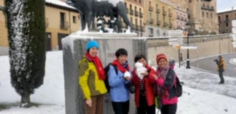 Un grupo de turistas orientales  posan con nieve en la mano frente a la estatua de la Loba Capitolina