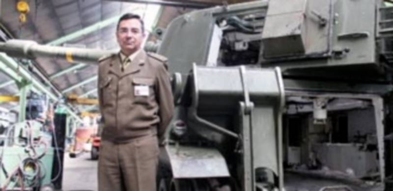 El coronel Segura Rius posa junto a un ATP M-109 actualmente en reparación en el centro fabril del parque segoviano./ M.G.