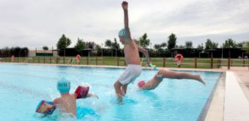 Los niños juegan en el agua de la piscina de Valverde del Majano para combatir el calor durante la época estival. / L. Mazagatos
