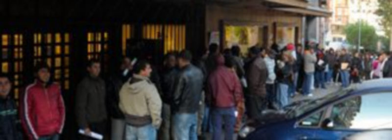 Una larga fila de personas espera para acceder a la oficina de empleo
