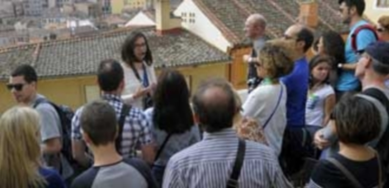 Un grupo de turistas atiende las explicaciones de una de las guías en su recorrido por Segovia. / Kamarero