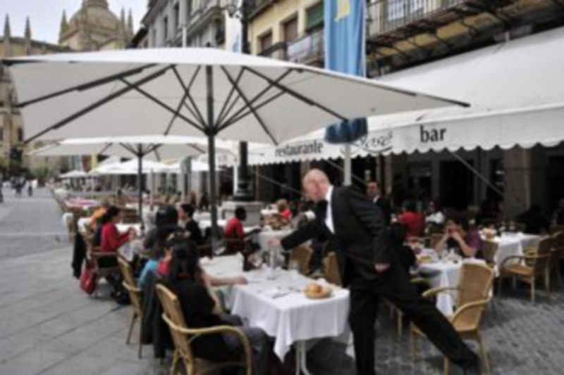 Un camarero del bar-restaurante José sirve a una mesa en la terraza