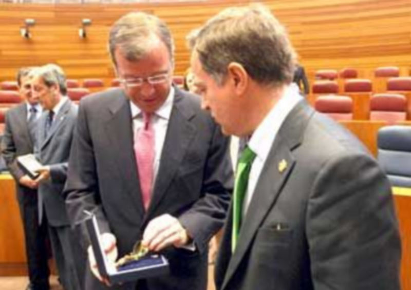 El procurador Antonio Silván muestra la medalla a Alejandro Valderas./ Ical.