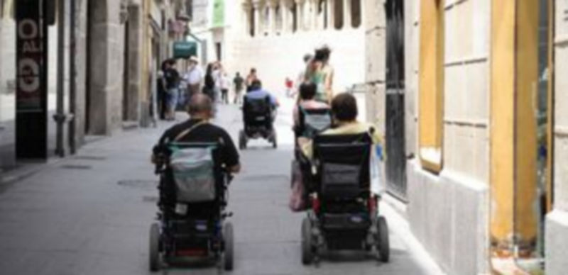 Un grupo de minusválidos pasea con sus sillas por la Calle Real