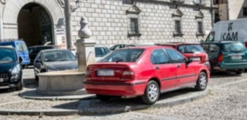 La presencia de vehículos en la plaza oculta en ocasiones elementos ornamentales como la fuente. / Kamarero