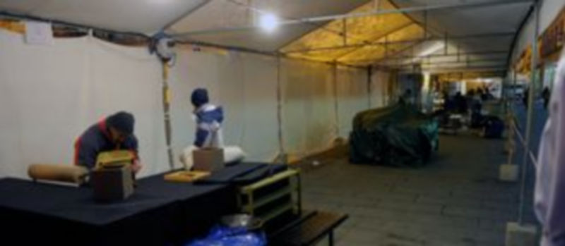 Trabajos de instalación de los expositores bajo la carpa que cubre el recinto de la feria de cerámica./Kamarero