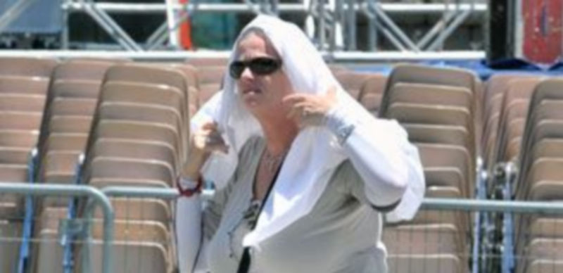 Una mujer cubre su cabeza para evitar el sol a su paso por el Azoguejo. / Kamarero.