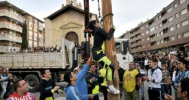 Un joven trepa por el Mayo para quitar la cadena de la grúa que lo ha transportando hasta la plaza./ Alberto Benavente