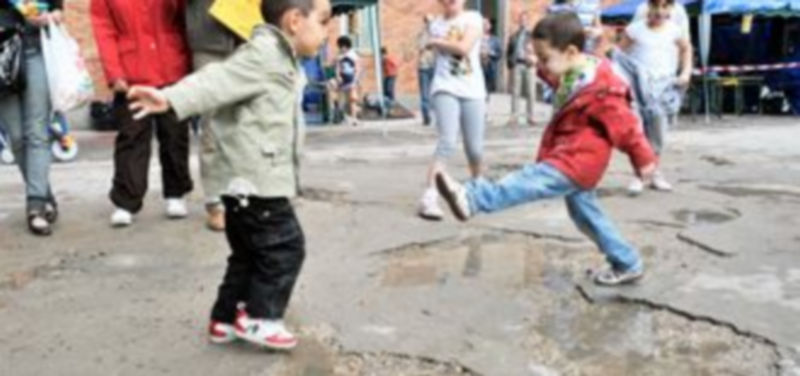 Unos niños juegan con los charcos que se forman como consecuencia de los desperfectos que tiene el pavimento./Kamarero