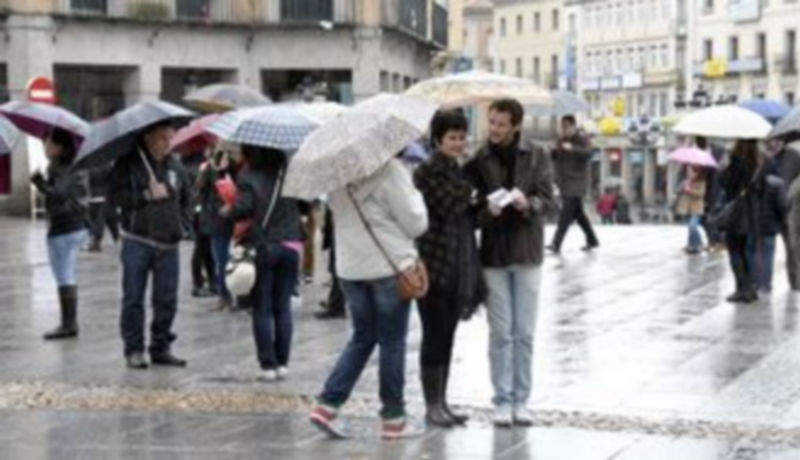 Varios turistas soportan la lluvia en una zona céntrica de la ciudad. / Juan Martin