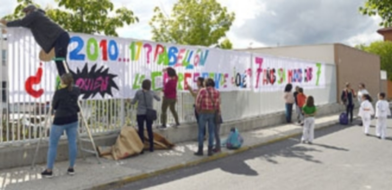 Padres y niños colocan pancartas en la valla del colegio pidiendo la apertura del pabellón. / Tamara de Santos