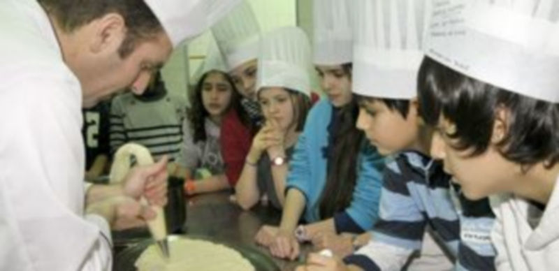 Los chavales observan atentamente el trabajo del chef Carlos Martín para el montaje del plato. / Alberto Benavente.