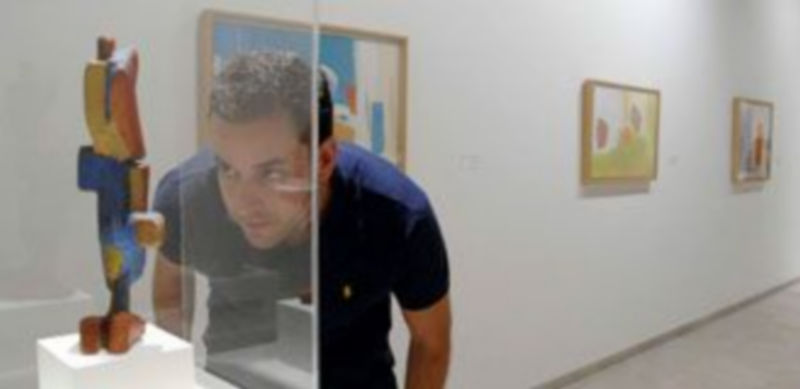 Un visitante contempla con detalle uno de los toys de Esteban Vicente; al fondo