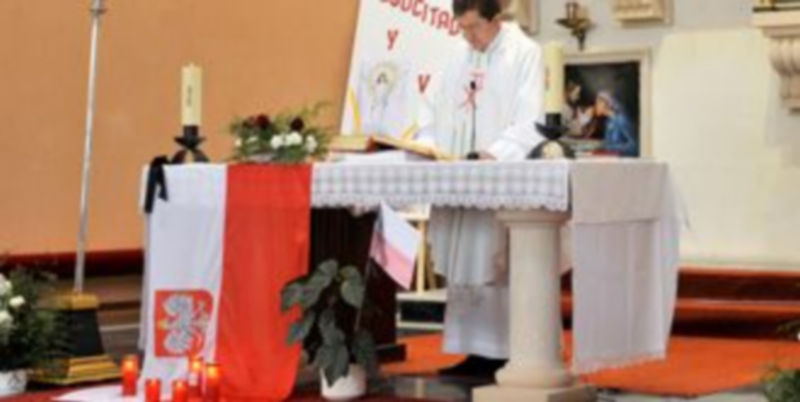 El sacerdote ofició la misa con una bandera polaca con crespón negro sobre el altar mayor. /Kamarero