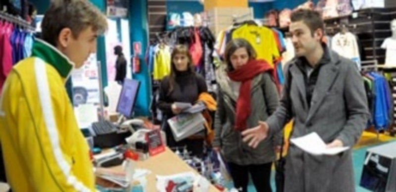 López Vela y Natalia del Barrio explican a un comerciante las medidas que Podemos propone./ Kamarero