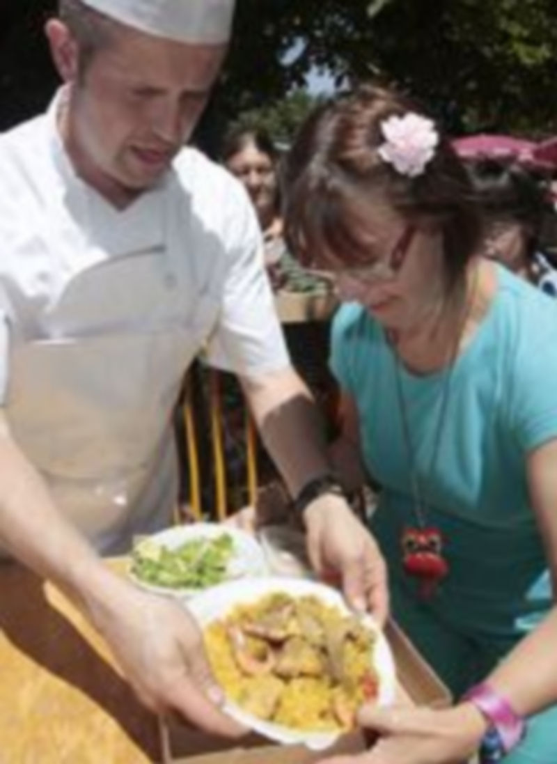 Un miembro de la Asociación de Cocineros de Segovia durante la repartición de platos de comida a uno de los asistentes a la tradicional paella. Foto: Lara mazagatos