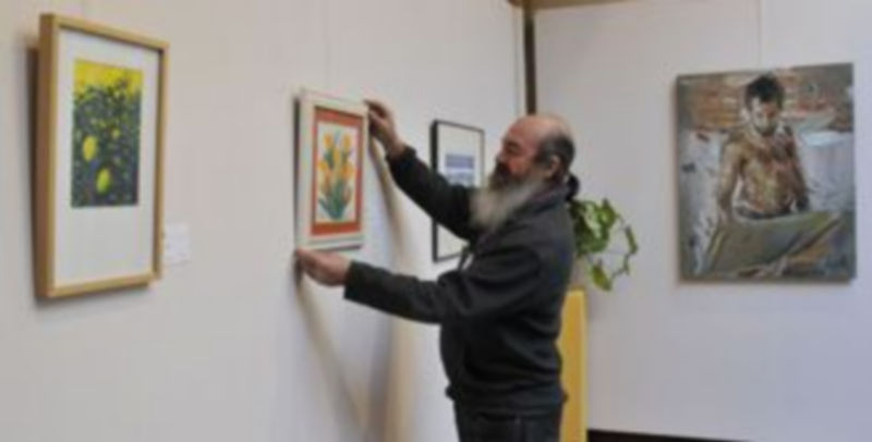 Luis Yuguero coloca uno de los cuadros que se pondrán a subasta el próximo jueves en la Casa de los Picos. / Juan Martín.