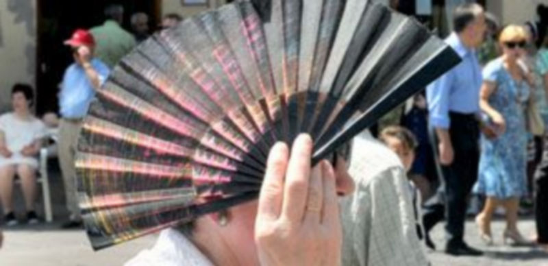 Una mujer se protege del sol con un abanico en la calle. / Kamarero