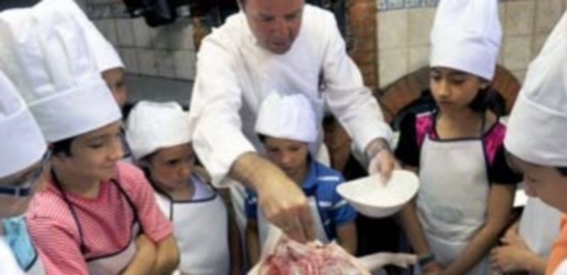 Los más pequeños con las manos en la masa 1 Cándido López enseña a los participantes del taller a preparar el cochinillo antes de asarlo. / Kamarero