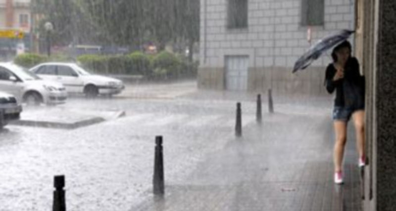 Una mujer intenta refugiarse de la lluvia en la Avenida de la Constitución. / Alberto Benavente