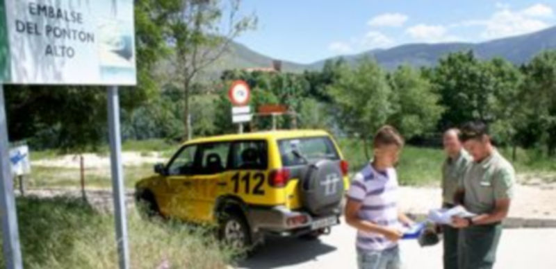 Agentes medioambientales distribuyen folletos informativos en el entorno del embalse a los visitantes de la zona. / E. A.