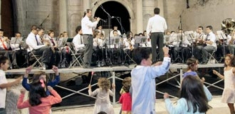 La Banda Municipal de Música con el pañuelo rojo al cuello e interpretando