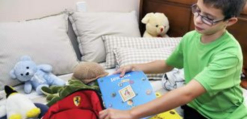 Un escolar prepara la mochila con los libros de texto para ir al colegio./ Alberto Benavente.