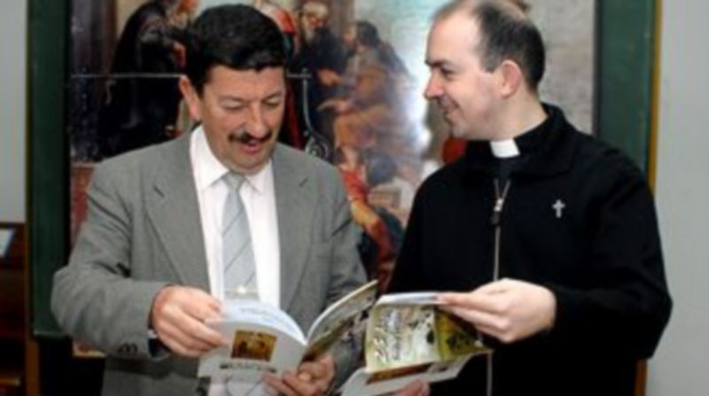 Alberto Herreras y el párroco Raúl Anaya hojean la publicación conmemorativa del aniversario./ALBERTO BENAVENTE
