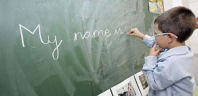 Un niño de Primaria escribe su nombre en inglés en la pizarra del aula. / Europa Press