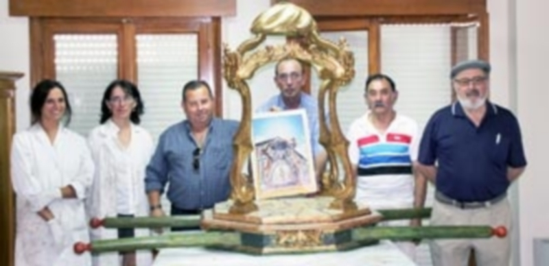 Algunos cofrades junto a las restauradoras y las andas ya en la fase final del proceso de restauración. / Chantal núñez