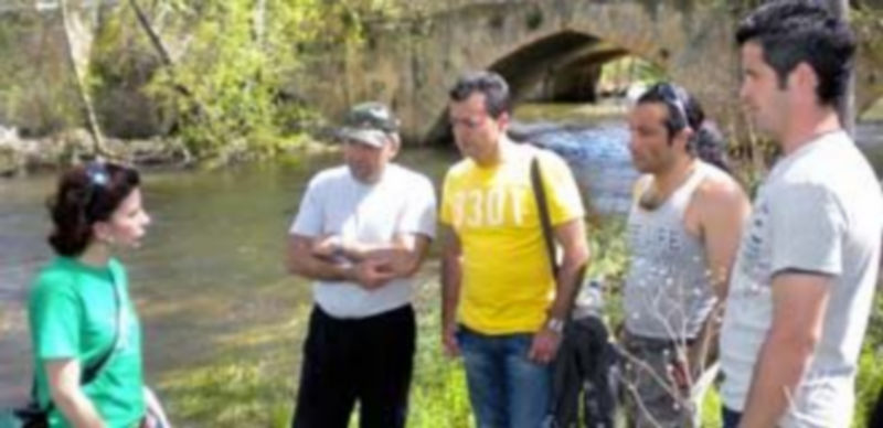 Una de las voluntarias de Cibya explica las técnicas de trabajo a los reclusos en la orilla del río. / M.G.