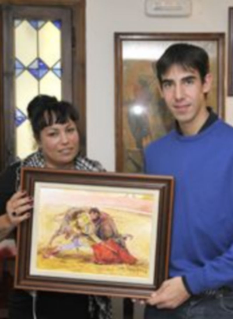 Jiménez Fortes junto a una guapa aficionada brasileña con el óleo de Lope Tablada. / Alberto Benavente