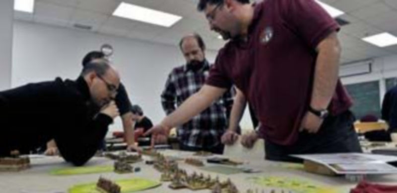 Un grupo de jugadores analiza las características del juego sobre el tablero. / Kamarero.