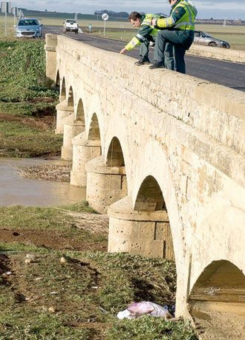 Dos guardias civiles miran el lugar donde quedó el coche. / EFE