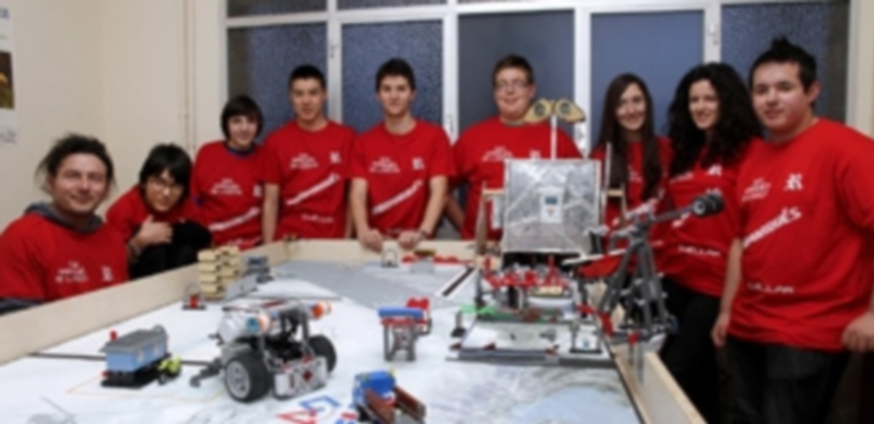 Los alumnos integrantes del los equipo y uno de sus entrenadores junto al tablero de juego en el que puede verse el robot construído./ Gabriel Gómez