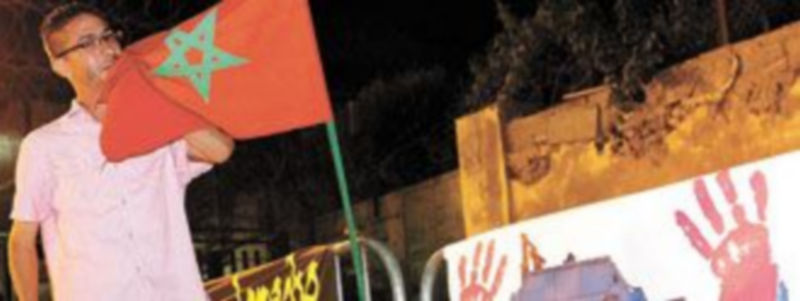 Un ‘activista’ besa la bandera de Marruecos junto al nuevo fotomontaje contra los policías españoles. / EFE