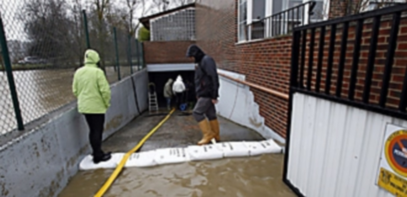 Varios vecinos colocan sacos para que el agua no entre en un garaje de Miranda de Ebro (Burgos) el pasado sábado. / Santi Otero/Efe