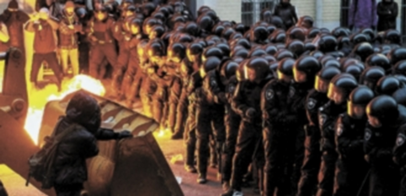 Agentes de las Fuerzas de Seguridad observan a un grupo de opositores quemar una excavadora durante una protesta en Kiev. / Reuters