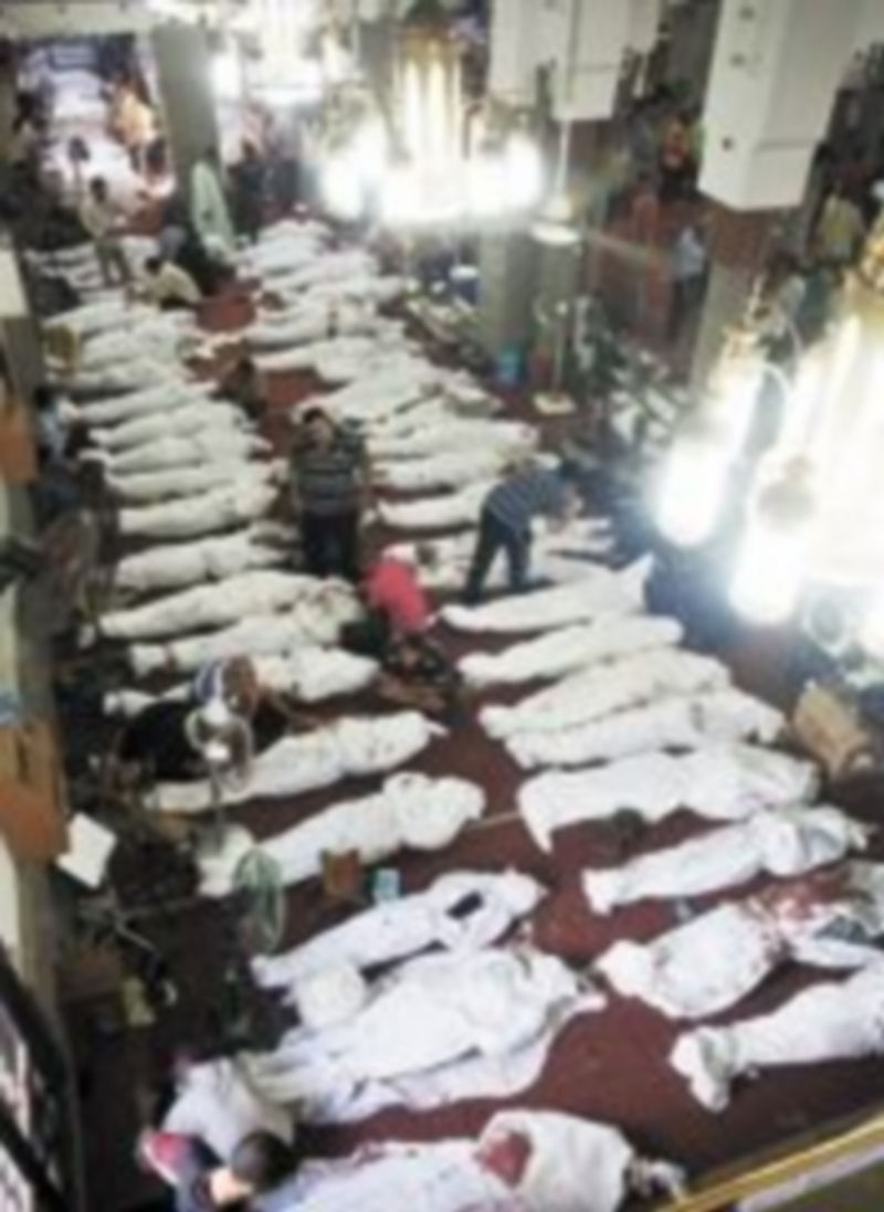 Varias personas permanecen junto a docenas de cadáveres de familiares en la mezquita al-Imene en El Cairo. / A. HAYMAN