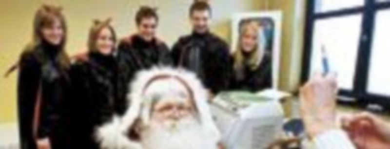 Una enfermera se prepara para vacunar de la gripe A a un hombre vestido de Papa Noel en presencia de sus ‘duendes’