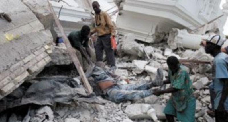 Unos hombres recuperan el cuerpo de un policía haitiano de entre los escombros de un edificio en la capital