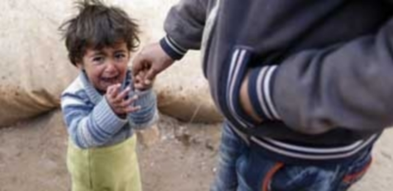 Un niño sirio llora junto a su padre en un campamento de refugiados situado en la frontera siria con Turquía / Efe.
