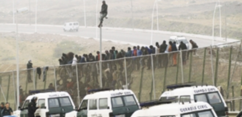Un abultado número de efectivos de la Guardia Civil vigila a los ‘sin papeles’ mientras permanecen encaramados a la valla de Melilla. / EFE