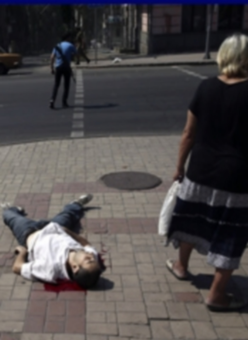 Una mujer permanece junto al cuerpo sin vida de un hombre tras los disparos realizados sobre la ciudad por parte del Ejército ucraniano. / Efe