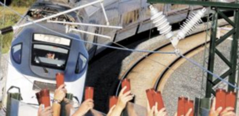 Vecinos de Angrois alzan los cirios mientras pasa un tren que hace la ruta del que descarriló la pasada semana. / Efe