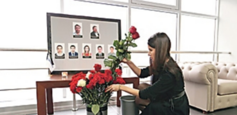 Una mujer coloca flores junto a las fotografías de la tripulación del Airbus A321 de Kogalimavia siniestrado en Egipto. / Efe