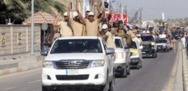 Voluntarios chiíes reclutados para luchar contra las fuerzas de seguridad iraquíes gritan eslóganes mientras patrullan