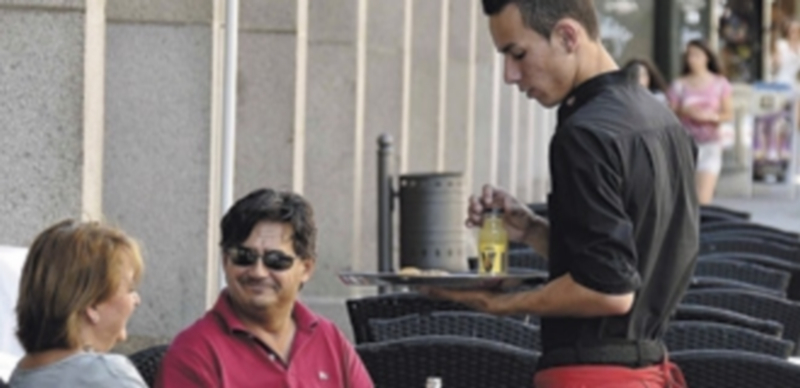 Un joven trabaja atendiendo a los clientes de un bar de la capital segoviana. / Juan Martín